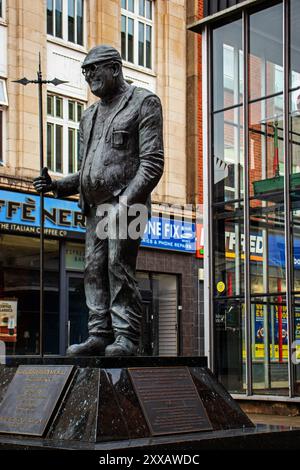 Thee statue of the famous Bolton steeplejack, Fred Dibnah standing ahead of a steam engine, and surrounded by shops in Bolton town centre Stock Photo