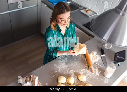 Young woman making croissants in kitchen at home. Stock Photo