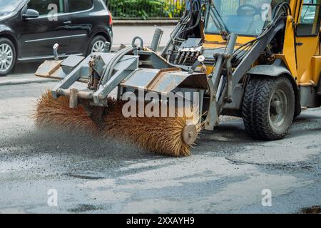 Road construction, tractor brushes the crushed stone from old asphalt before laying new Stock Photo