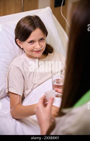 Woman gives medicine and water to a young patient Stock Photo