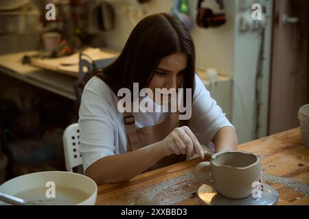 Woman ceramist in the workshop making mug out of clay Stock Photo