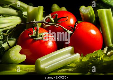 tomato branch sliced celery sticks on black background Stock Photo