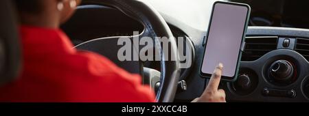 Header image with closeup of female delivery driver using GPS navigation system or mobile app tapping white blank screen on smartphone Stock Photo