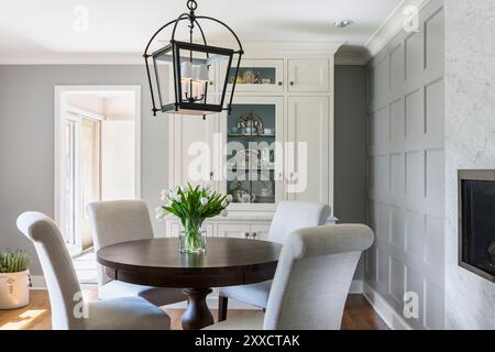 Round table and chairs in dining area of kitchen with white cabinet in background Stock Photo
