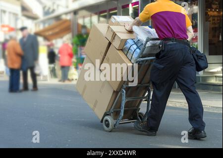 Postman transports parcels through the city on a trolley Stock Photo