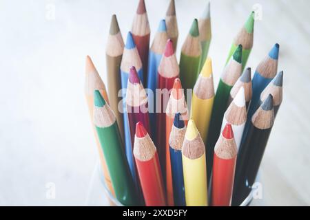 Colored pencils in a can on rustic wooden table, white background Stock Photo