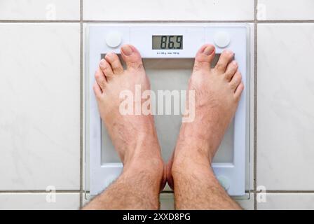 Men's feet on a bathroom scale Stock Photo