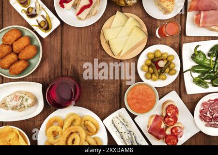 The food of Spain. An overhead photo of many different Spanish tapas, shot from above on a dark rustic texture. Jamon, cheese, wine, olives, croquette Stock Photo
