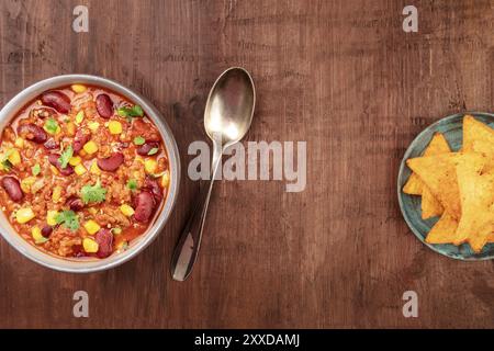 Mexican food design template. Chili con carne with nachos, tortilla chips, shot from above on a dark rustic wooden background with copy space Stock Photo