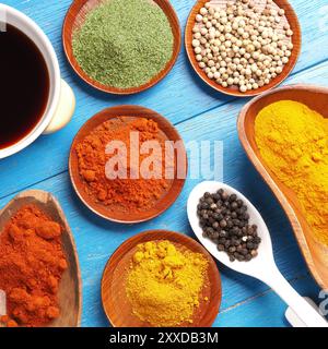 Colorful assortment of herbs and spices on a blue wooden table, top view Stock Photo