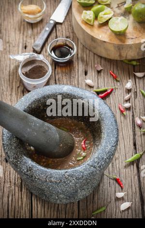 Shrimp paste chilli sauce in a mortar stone with Ingredients to cook Stock Photo