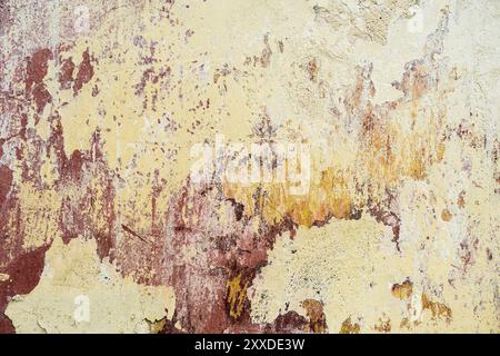 Textured background of multi-layer flaking paint on the wall. Mixing different colors of paints in the cleaved layers on the surface. Grunge texture w Stock Photo