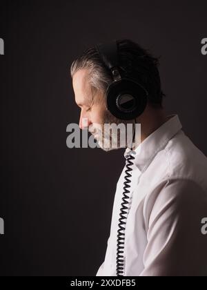 Handsome man with vintage studio headphones on a dark background Stock Photo