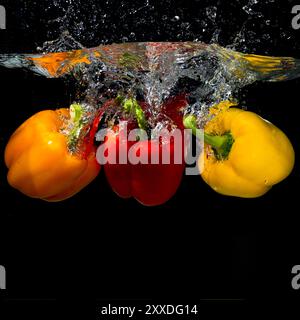 Three bell peppers falling into splash water Stock Photo