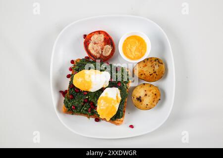 Healthy toast bread with spinach, fried eggs, pomegranate seed and fresh spinach. Delicious breakfast or snack isolated on white background Stock Photo