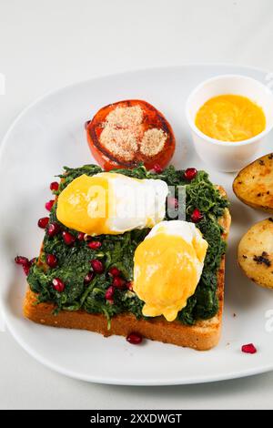 Crostini roasted bread slices with cooked spinach leaves and fried eggs seasoned with potato, Selective Focus Stock Photo