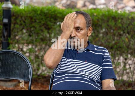 isolated old man having eye strain at outdoor park at evening from flat angle Stock Photo