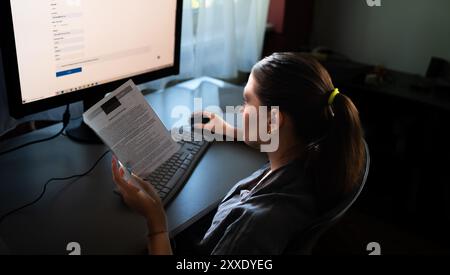 A young woman is sitting at a computer in the office, doing graphic design Stock Photo