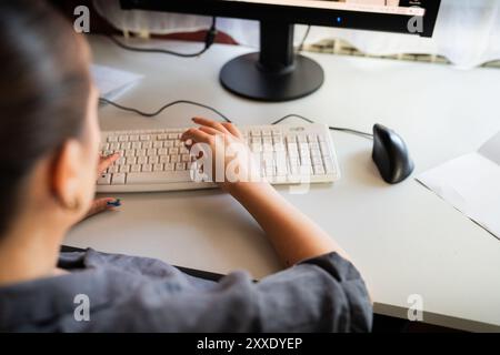 A young woman is sitting at a computer in the office, doing graphic design Stock Photo
