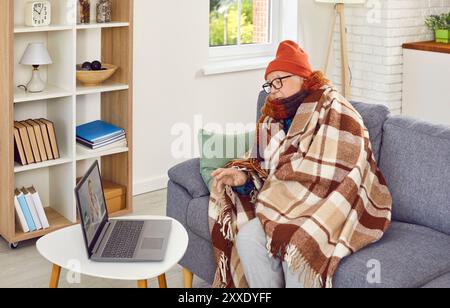 Sick senior man talking about the symptoms of illness having online video call with doctor at home. Stock Photo