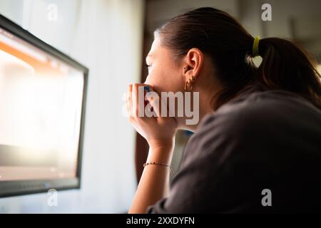 A young woman is sitting at a computer in the office, doing graphic design Stock Photo