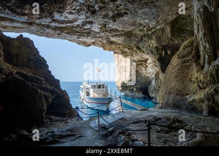 Alghero, Italy - August 25, 2023: Boat waiting for the tourist of the guide visit, view from inside the Grotto of Neptune (Grotta di Nettuno) on the i Stock Photo