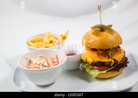 Burger with fried potatoes and tomato sauce on restaurant table. Cheeseburger, beef burger with cheese, bacon, tomatoes, cucumber, onion and lettuce Stock Photo