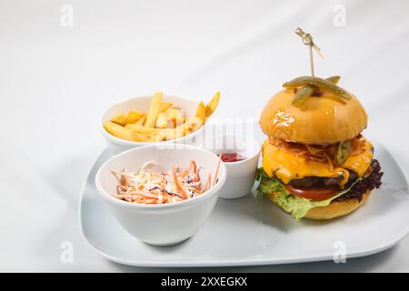 Burger with fried potatoes and tomato sauce on restaurant table. hamburger, beef burger with cheese, bacon, tomatoes, cucumber, onion and lettuce Stock Photo