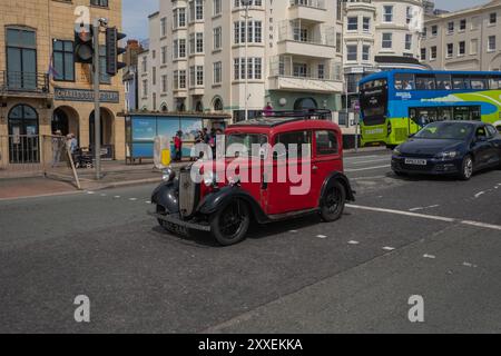 A red Austin seven classic car drives along Brighton seafront on a sunny summers day. Stock Photo