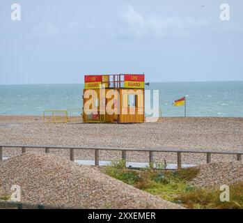 A empty Lifeguard station container on Brighton Beach England next to a warning  flag with sea horizon in the background. Stock Photo