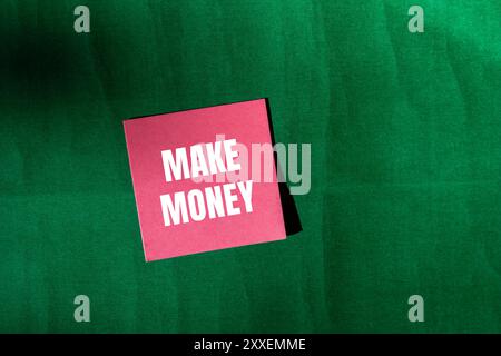 Make money message written on pink paper with green background. Conceptual make money symbol. Copy space. Stock Photo