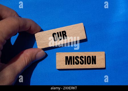 Our mission message written on wooden blocks with blue background. Conceptual our mission symbol. Copy space. Stock Photo