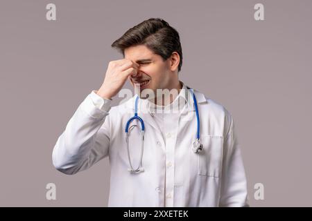 30s aged physician man in white medical coat form having headache, studio portrait. Guy putting hands on head, isolated on white background. Concept o Stock Photo