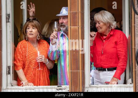 Manchester, UK. 24th Aug, 2024. Members of the public view the parade from a window at the Midland Hotel where a Pride party is taking place. Palestinian protesters failed to prevent Pride Parade taking place after they blocked road on Peter Street by laying in road. They were objecting against Booking.com who also carry adverts for properties in Israel. The police moved in and cleared the protest allowing the protest to proceed. Some individuals in the parade where carrying Palestinian flags.Manchester Pride 2024 . This year's theme is 'Buzzin To Be Queer - A Hive of Progress' . Credit: GaryR Stock Photo