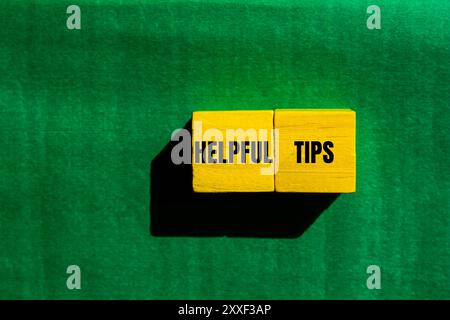 Helpful tips message written on yellow wooden cubes with green background. Conceptual helpful tips symbol. Copy space. Stock Photo