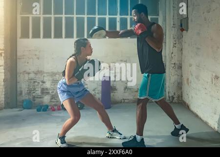 Pretty young woman trains in boxing sparring with male. Stock Photo
