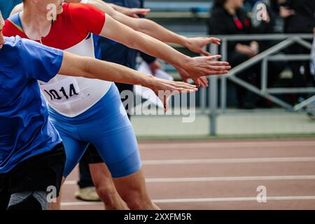 four hands of athletes waiting to pass baton in athletics competition Stock Photo