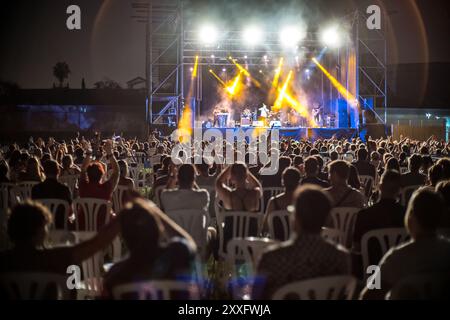 An exciting nighttime rock concert with a large, energetic audience enjoying live music under colorful stage lights. The atmosphere is vibrant and fil Stock Photo