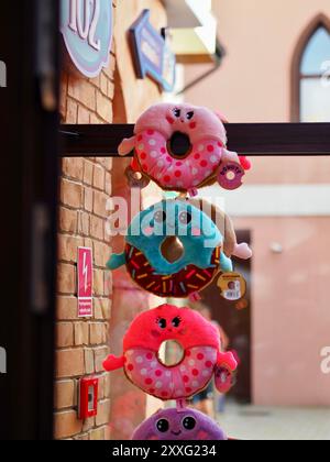 Energylandia, Poland - August 23, 2024: Three soft beautiful plush pink and blue donut toys in amusement park. Stock Photo