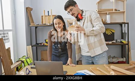 Woman and man inspecting a wooden object in a well-equipped carpentry workshop. Stock Photo