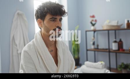 Handsome young man with beard in spa wellness center wearing white bathrobe Stock Photo