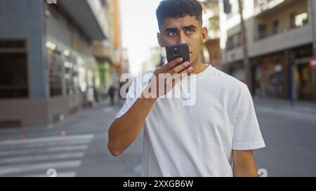 Young man using smartphone on bustling city street Stock Photo