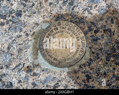 Summit marker proudly stands at the peak of Cascade Mountain, surrounded by rugged stones in Lake Placid, New York State. Stock Photo