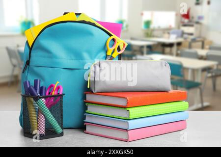 Light blue backpack with stationery on school desk in classroom Stock Photo