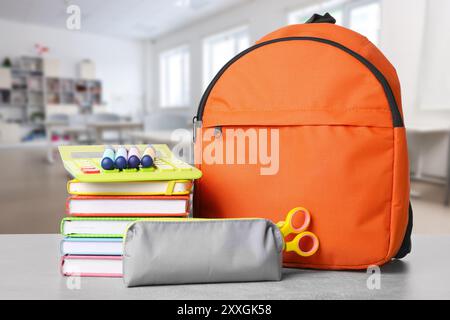 Orange backpack with stationery on school desk in classroom Stock Photo