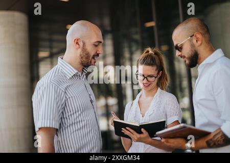 Businesspeople having an outdoor meeting in an urban downtown area, discussing and reviewing notes Stock Photo