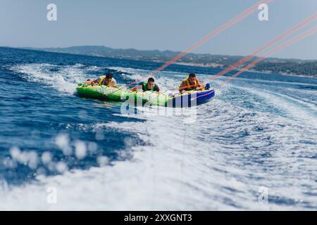 Three people enjoying summer tubing on a speedboat in the sea Stock Photo