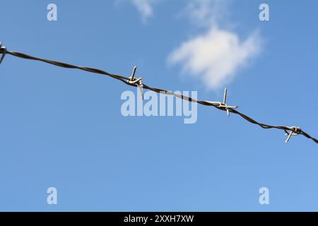 Barbed wire on the fence in front of a private property Stock Photo