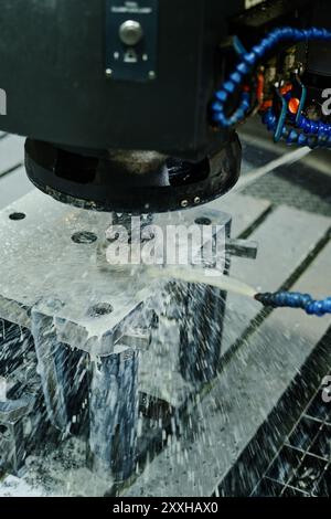 Advanced machinery using high-pressure water jets for cutting metal parts with precision in industrial setting. Metal being cooled and shaped during cutting process Stock Photo