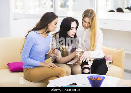 Happy girls talking, trying cosmetics and drinking champagne Stock Photo